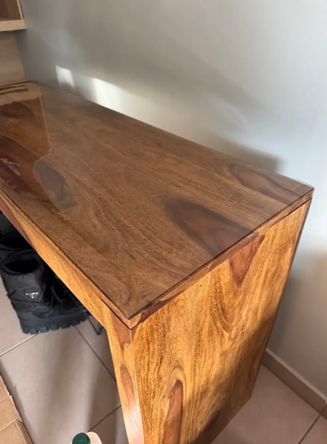 Schmale Konsole aus dunklem, poliertem Holz, mit weichem Glas bedeckt, an einer weißen Wand