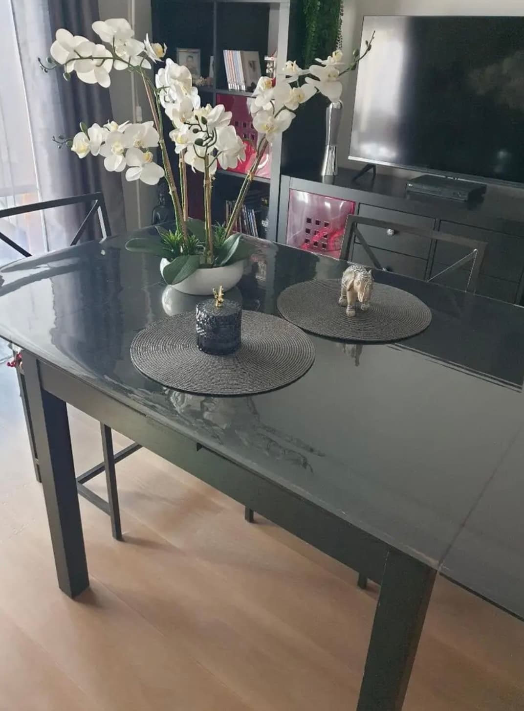 Graphitfarbener Wohnzimmertisch mit weißer Orchidee und runden Untersetzern, die Platte unter der Matte