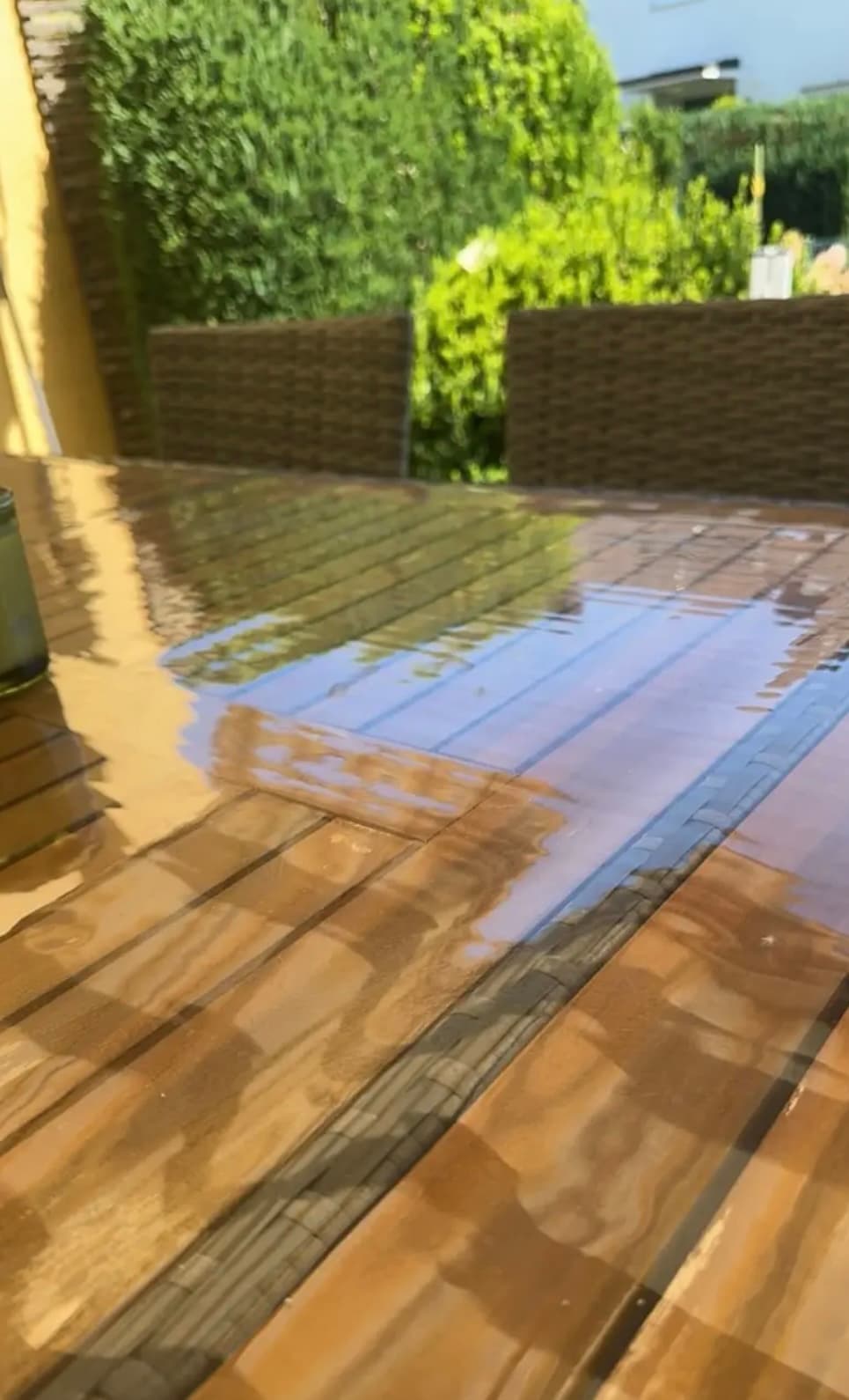 Gartentisch aus Holzleisten; in der Matte spiegeln sich Hecke und Himmel