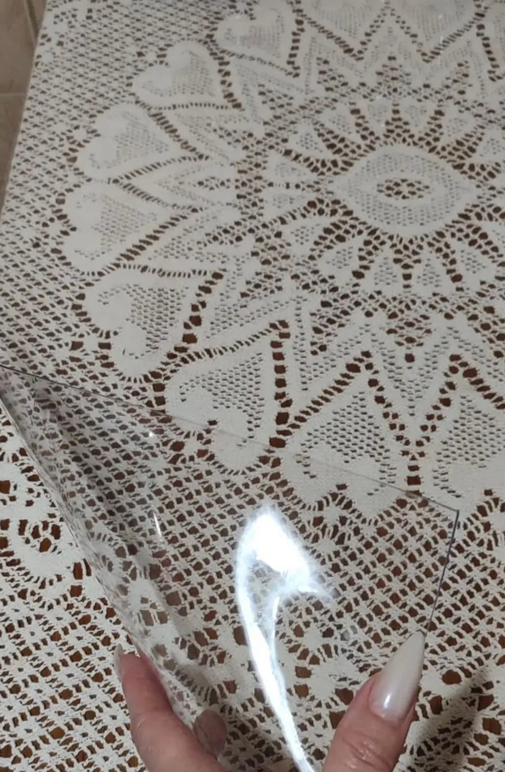 Transparente Matte auf einer gehäkelten Tischdecke — das Spitzenmuster ist durch die Auflage sichtbar