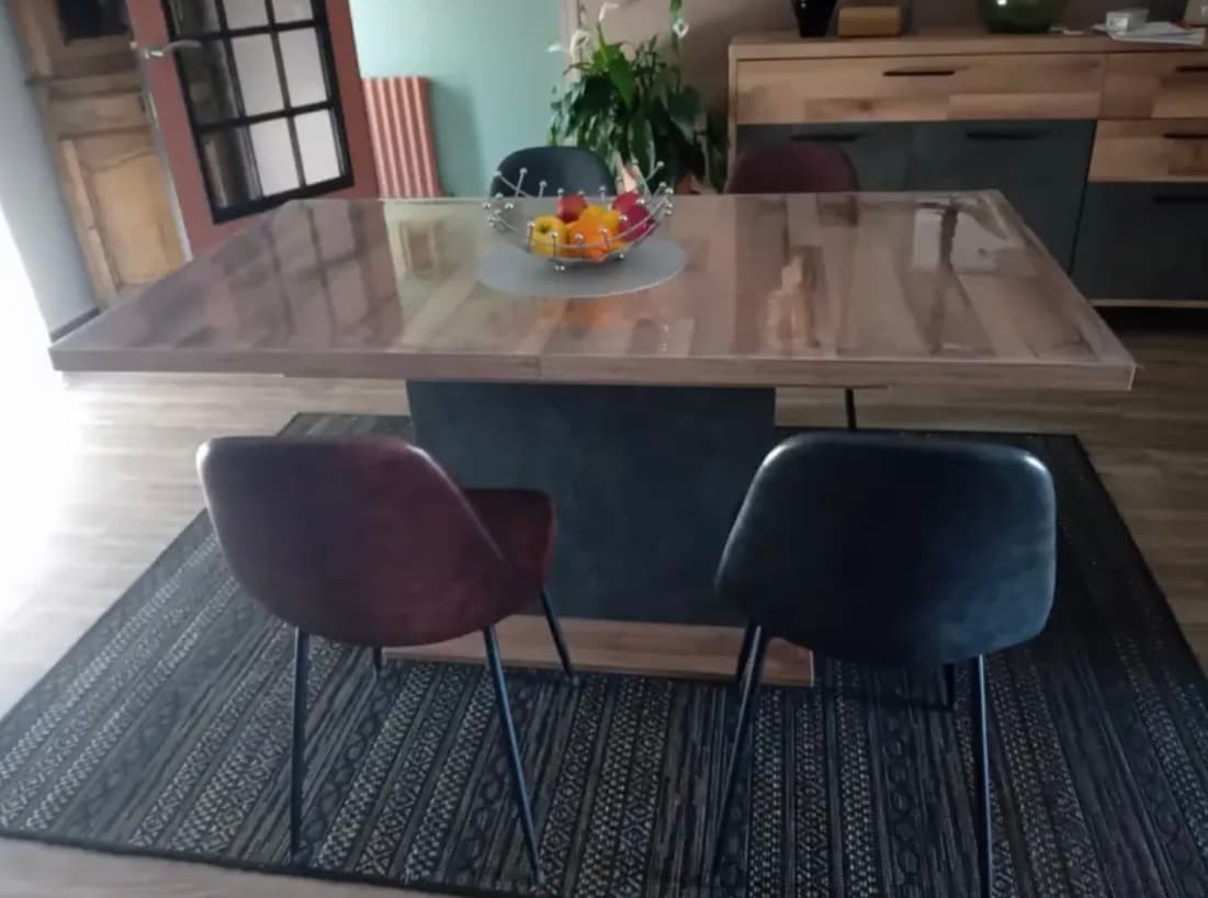 Ausziehtisch aus astigem Holz mit Obstkorb; zwei Lederstühle auf dem Teppich