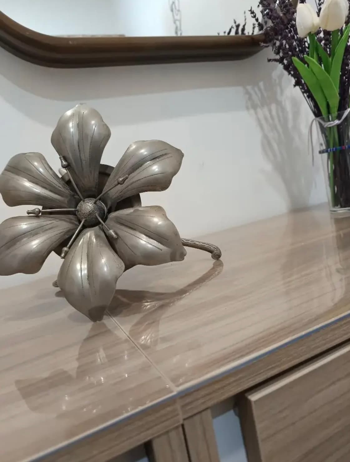 Helle Kommode mit floraler Metalldeko und Tulpen; die Platte mit weichem Glas bedeckt
