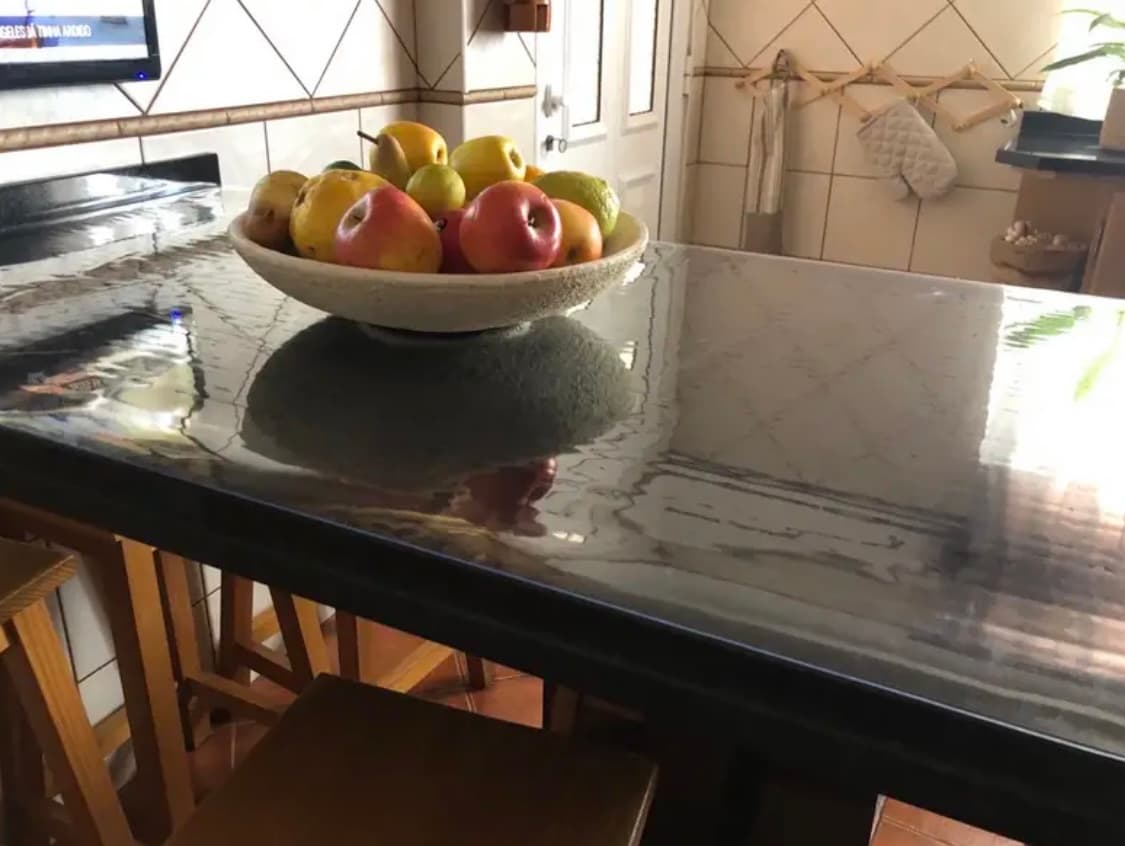 Kücheninsel mit Platte in Marmoroptik — eine Schale mit Äpfeln und Birnen steht auf der Matte